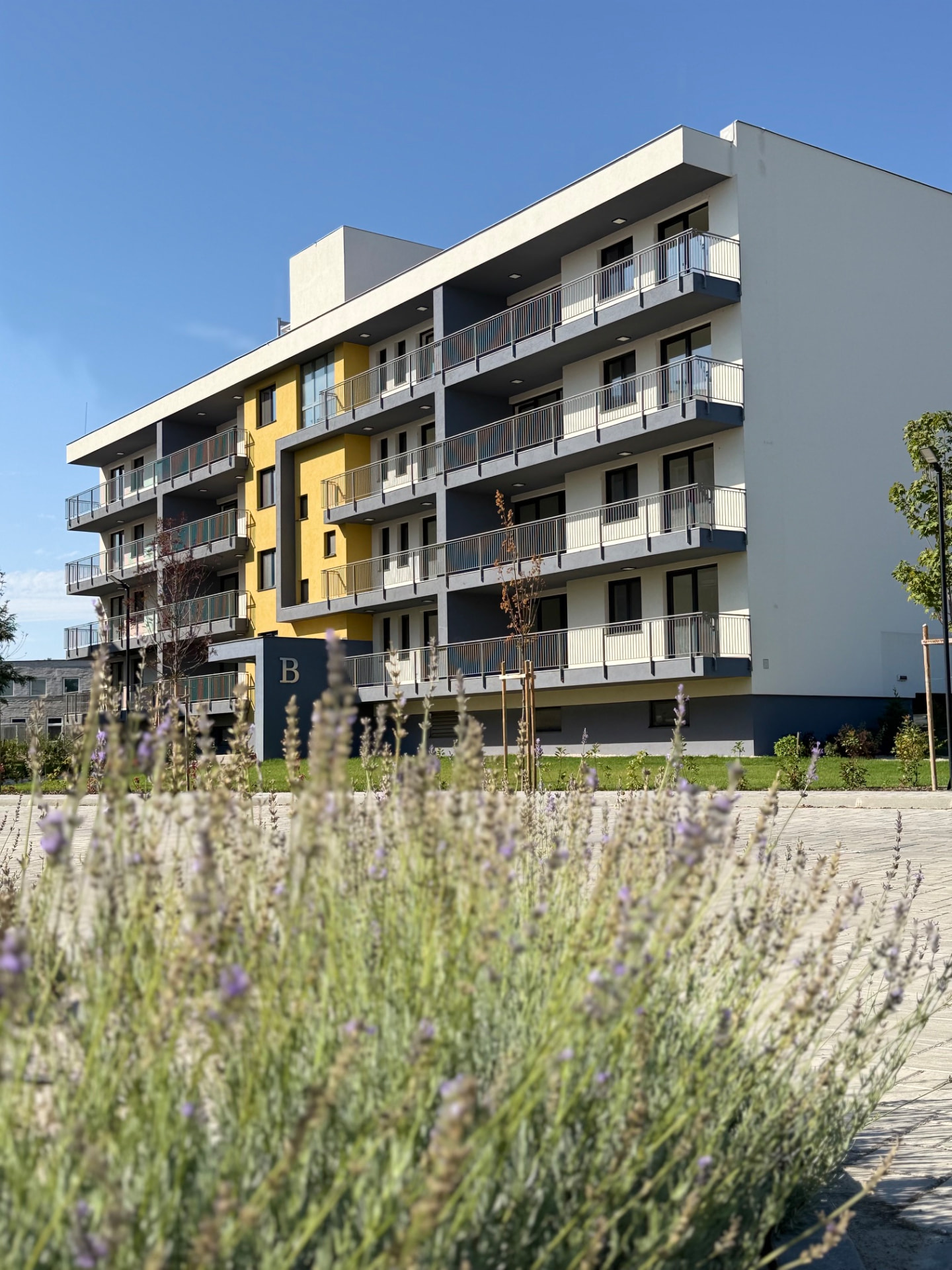 A Horizont Lakópark látványterve: többszintes, erkélyes lakóépület parkosított, fás környezetben